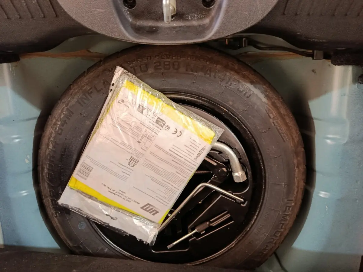 Gros plan sur la roue de secours noire dans le coffre bleu clair d'une FIAT 500 Hybrid 2022.