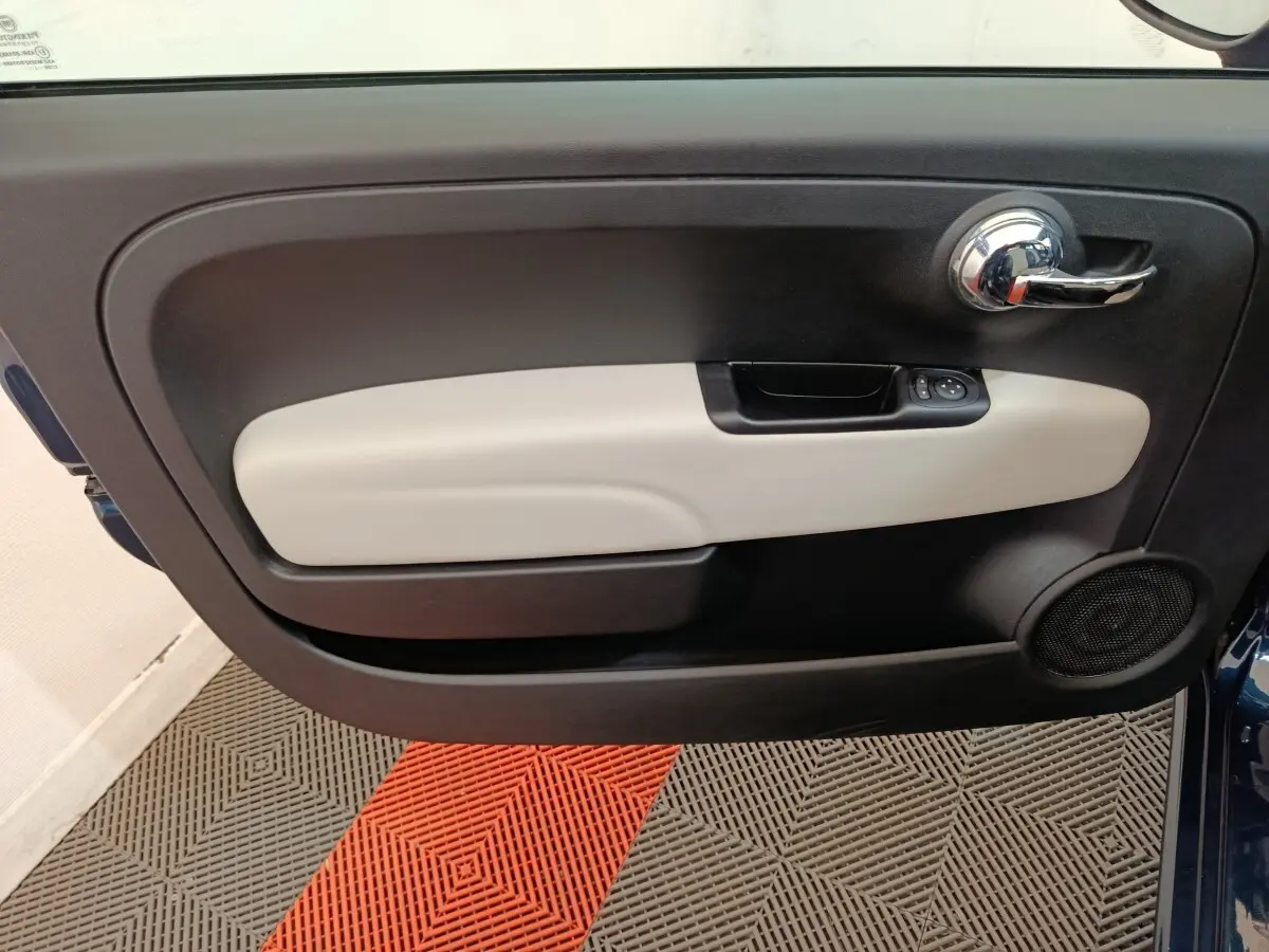 Vue intérieure du panneau de porte avant gauche de la FIAT 500 bleu, avec poignée chromée et commande de vitres.