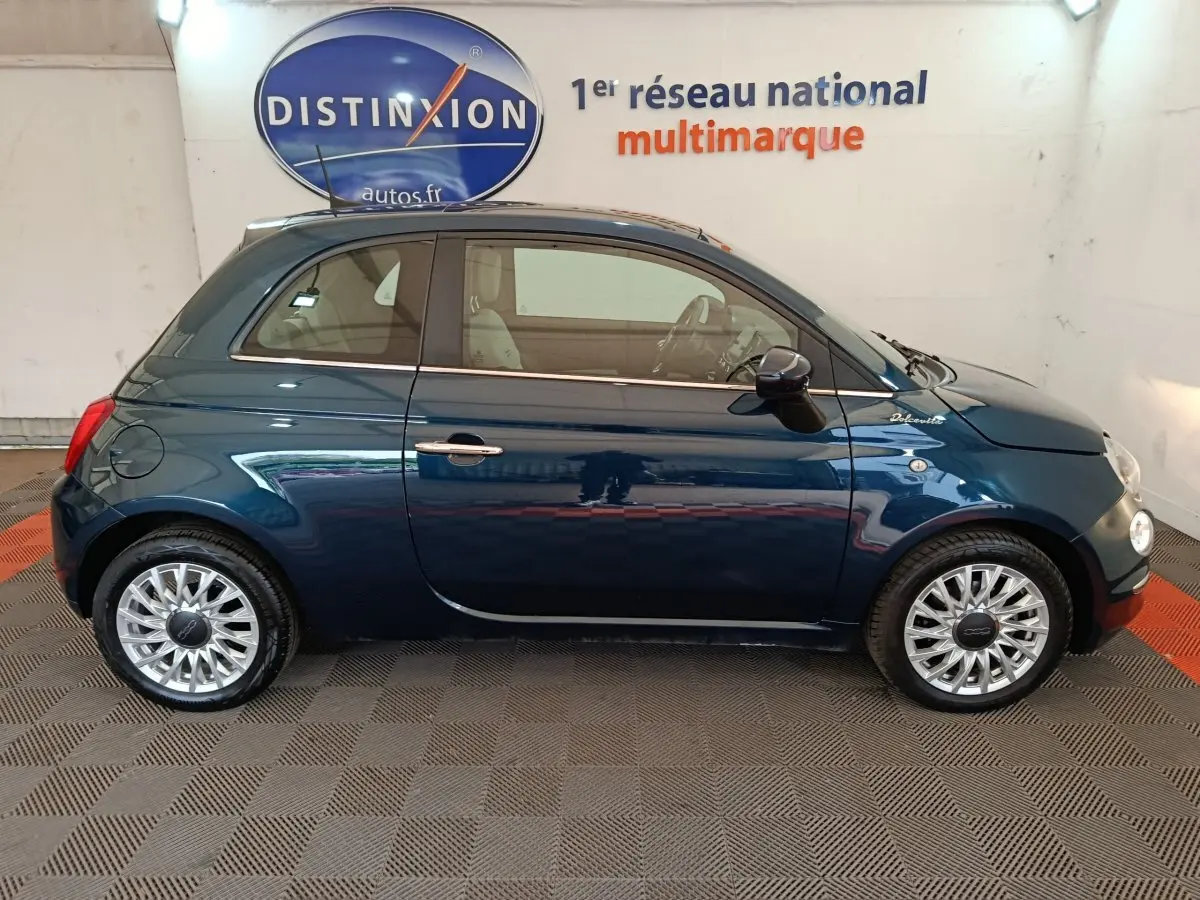 Profil droit d'une FIAT 500 Dolcevita bleu profond, avec jantes alliage et logo distinctif sur l'aile avant.