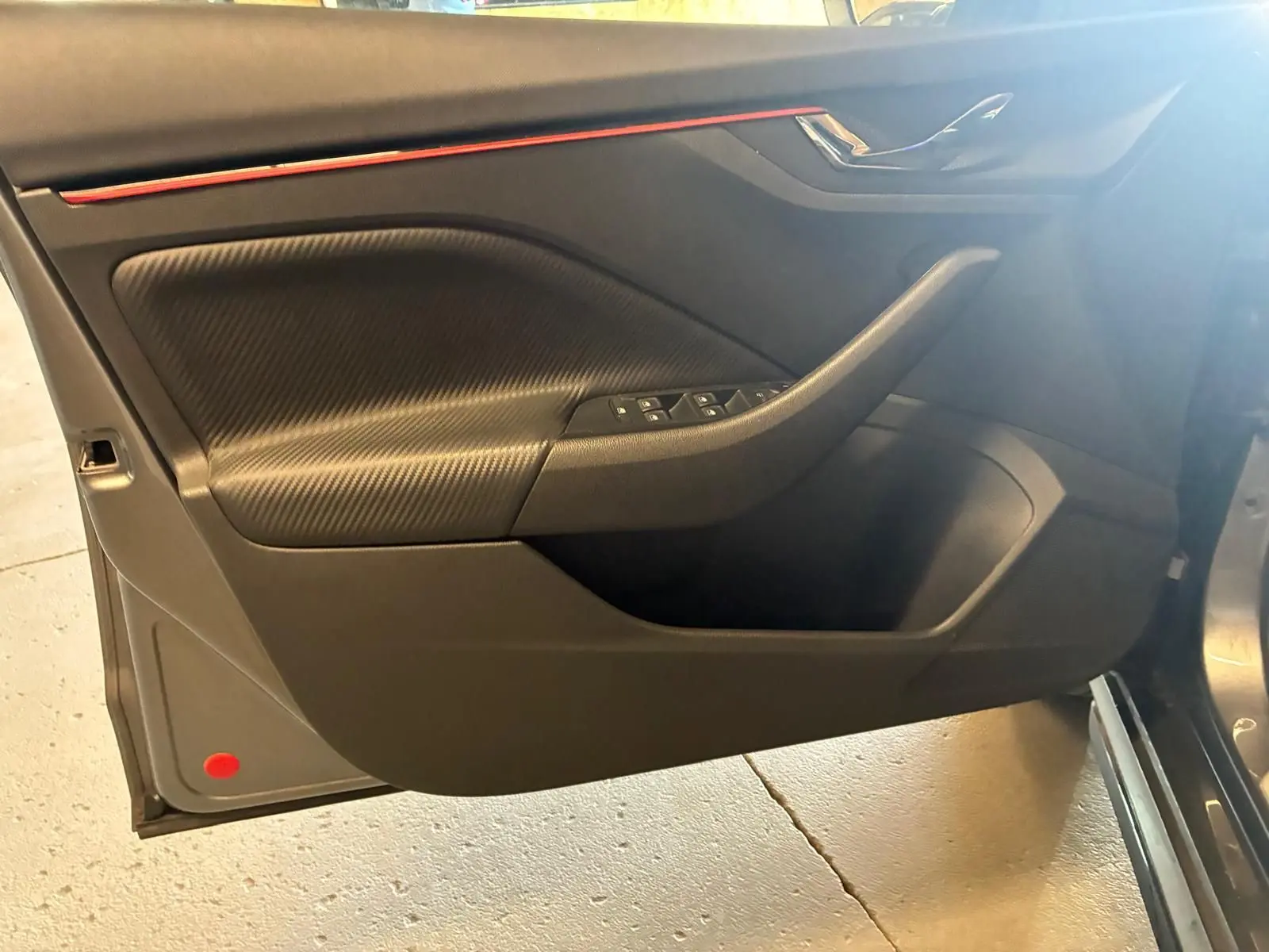 Vue intérieure côté gauche de la porte avant d'une Skoda Kamiq gris foncé, avec insert texturé et commandes de vitres.