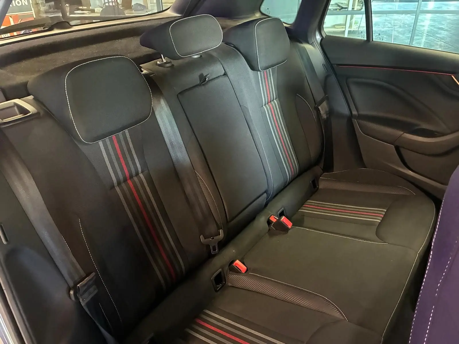 Vue intérieure arrière du Skoda Kamiq 2024 gris foncé, sièges tissu noir avec bandes rouges et grises distinctives.