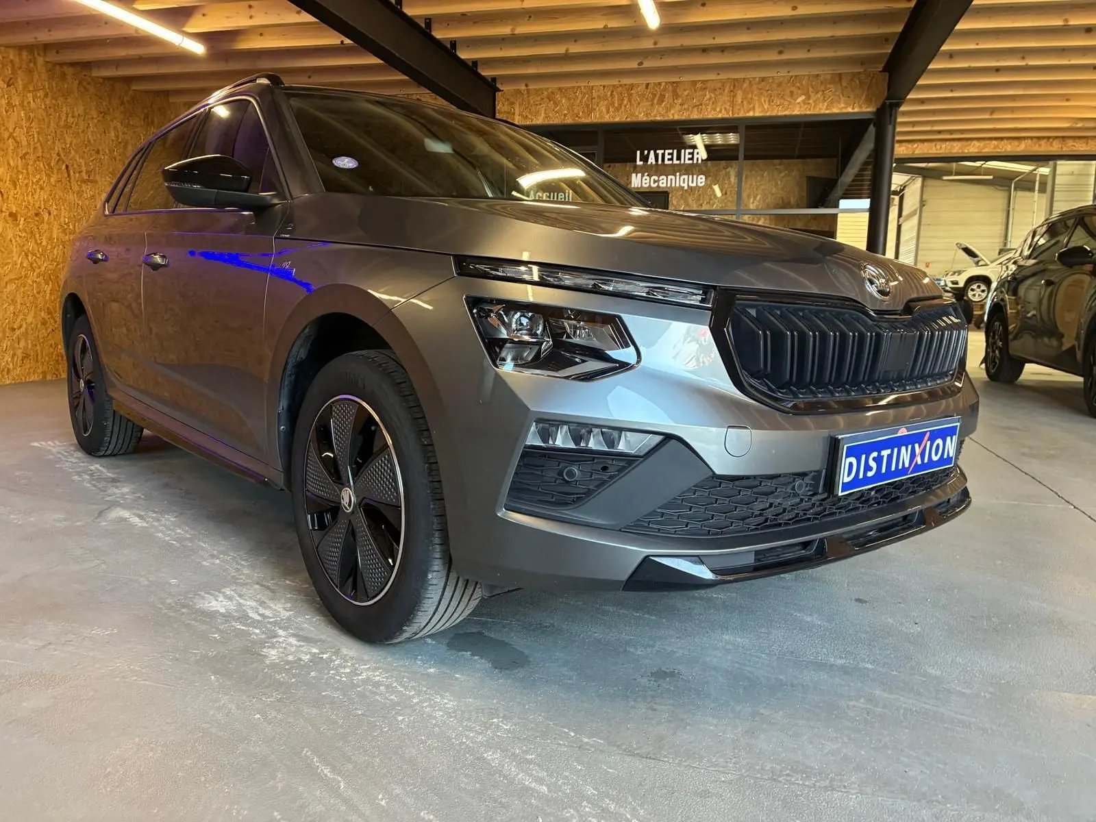 Skoda Kamiq 1.5 TSI 2024 gris foncé en 3/4 avant gauche, avec calandre noire et jantes spécifiques Monte-Carlo.