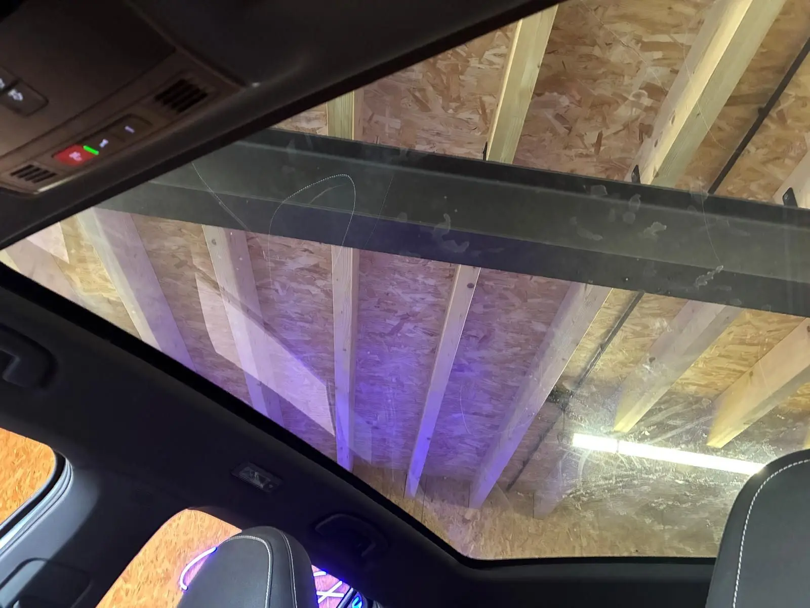 Toit panoramique en verre du Skoda Kamiq gris foncé 2024, vue intérieure vers le plafond en bois d'atelier.