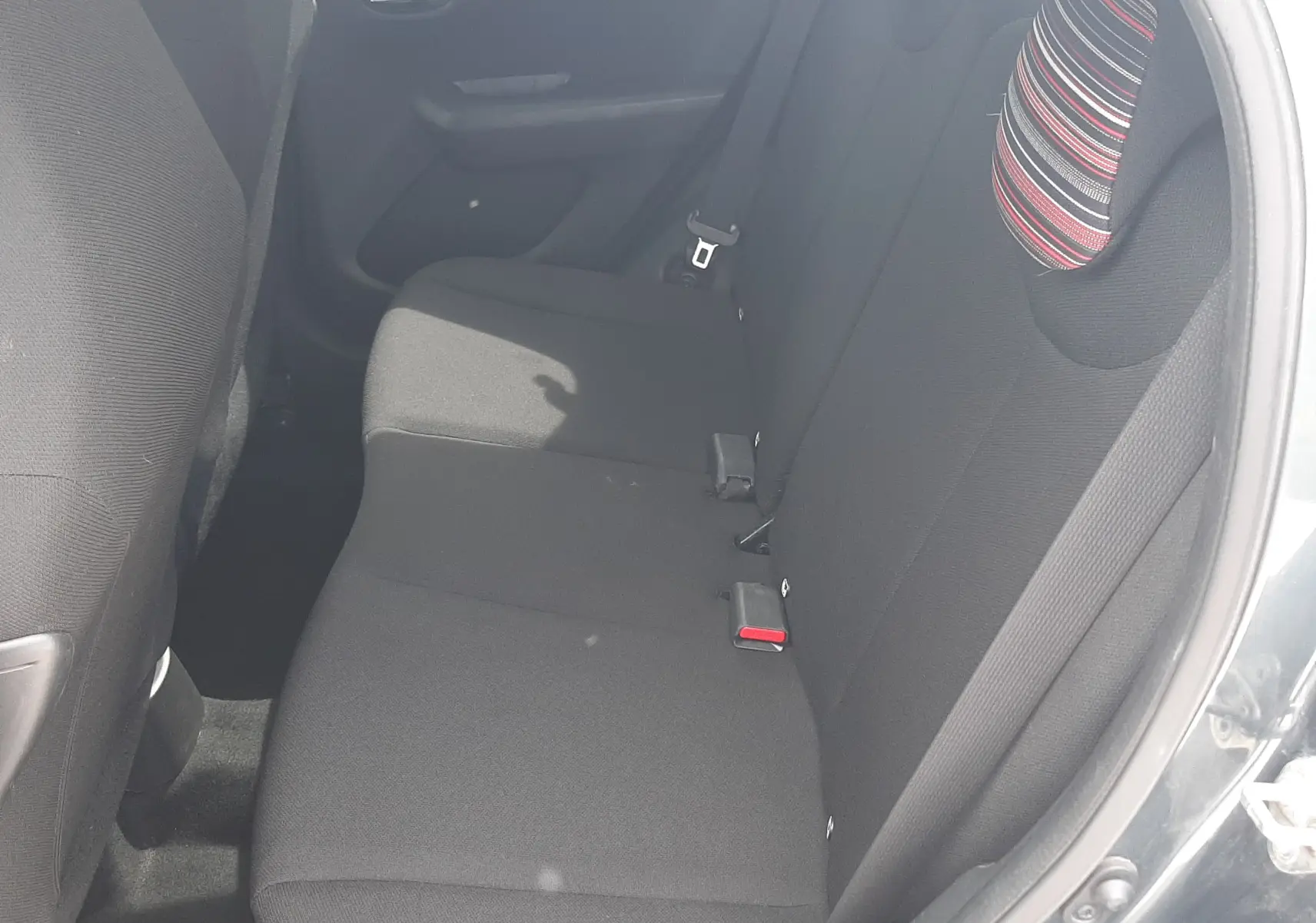 Vue intérieure côté droit sur la banquette arrière noire avec appuie-têtes rayés d'une Citroën C1 gris foncé 2019.