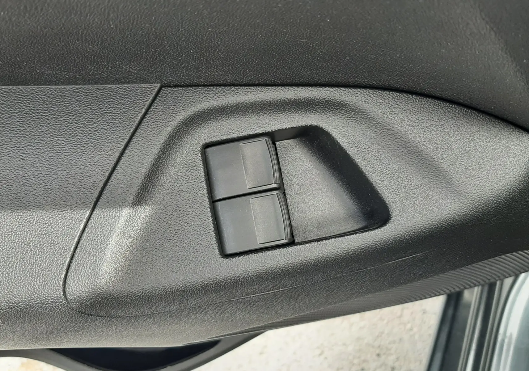 Gros plan sur les commandes des vitres électriques côté conducteur d'une Citroën C1 gris foncé 2019.