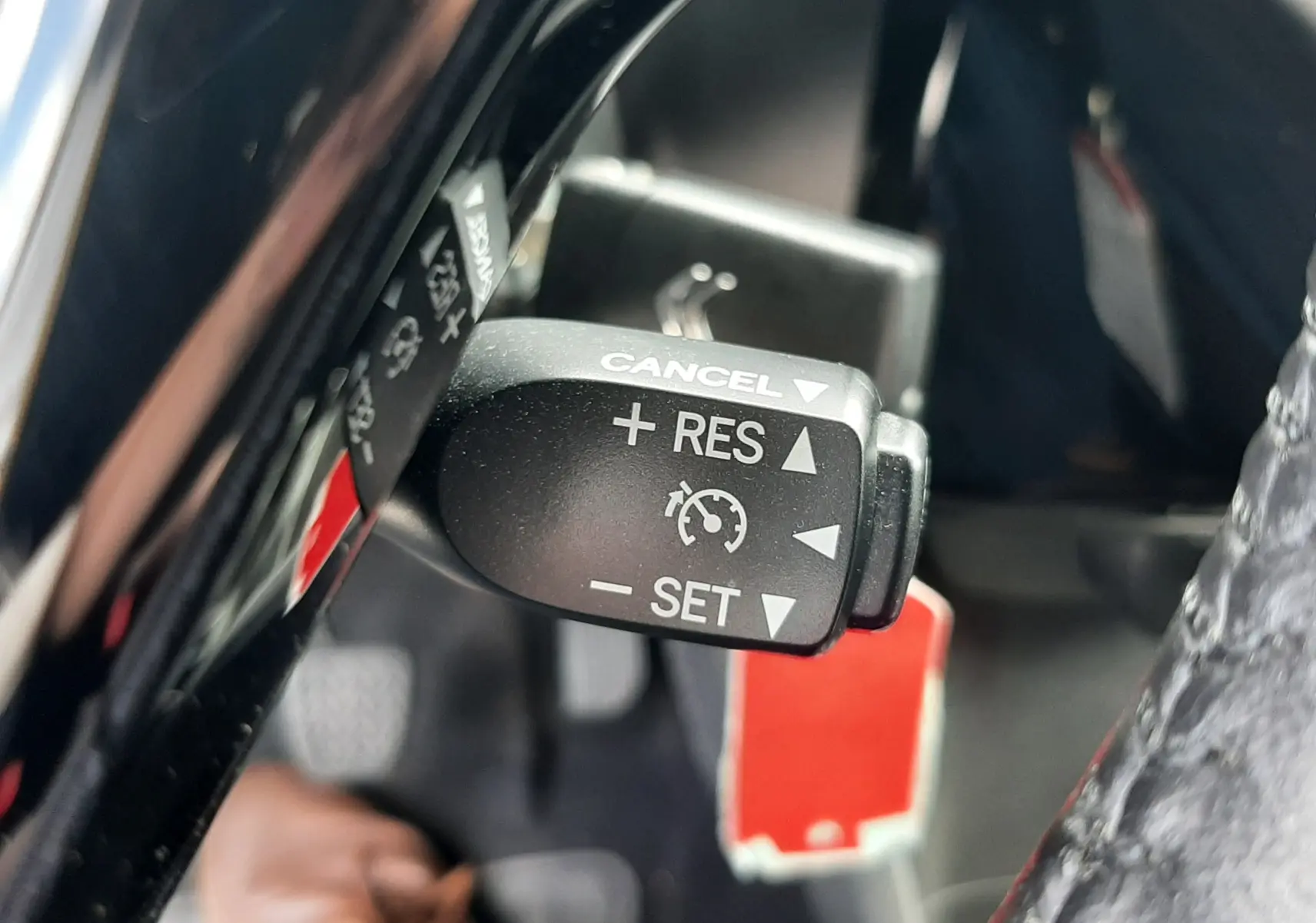 Gros plan sur la commande de régulateur de vitesse dans l'habitacle d'une Citroën C1 gris foncé, version Shine 2019.