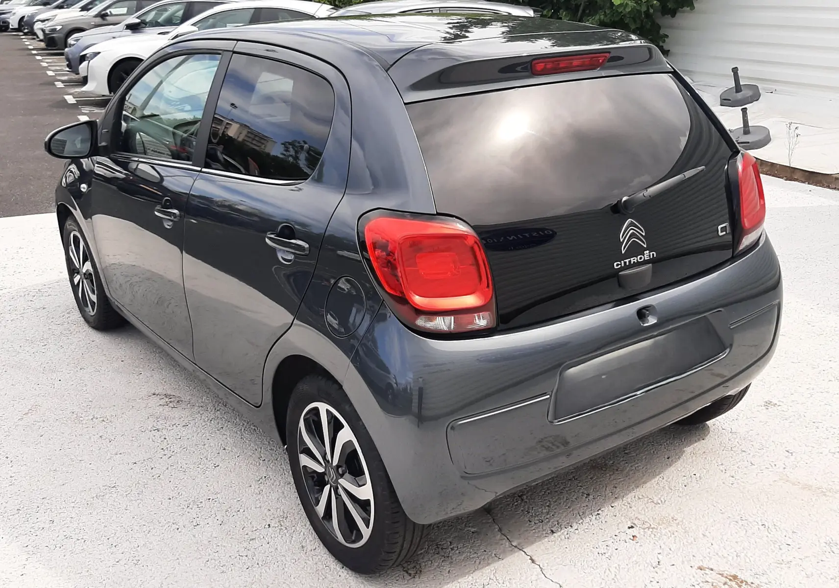 Vue 3/4 arrière droite d'une Citroën C1 gris foncé 5 portes avec feux arrière rouges et jantes bi-ton.
