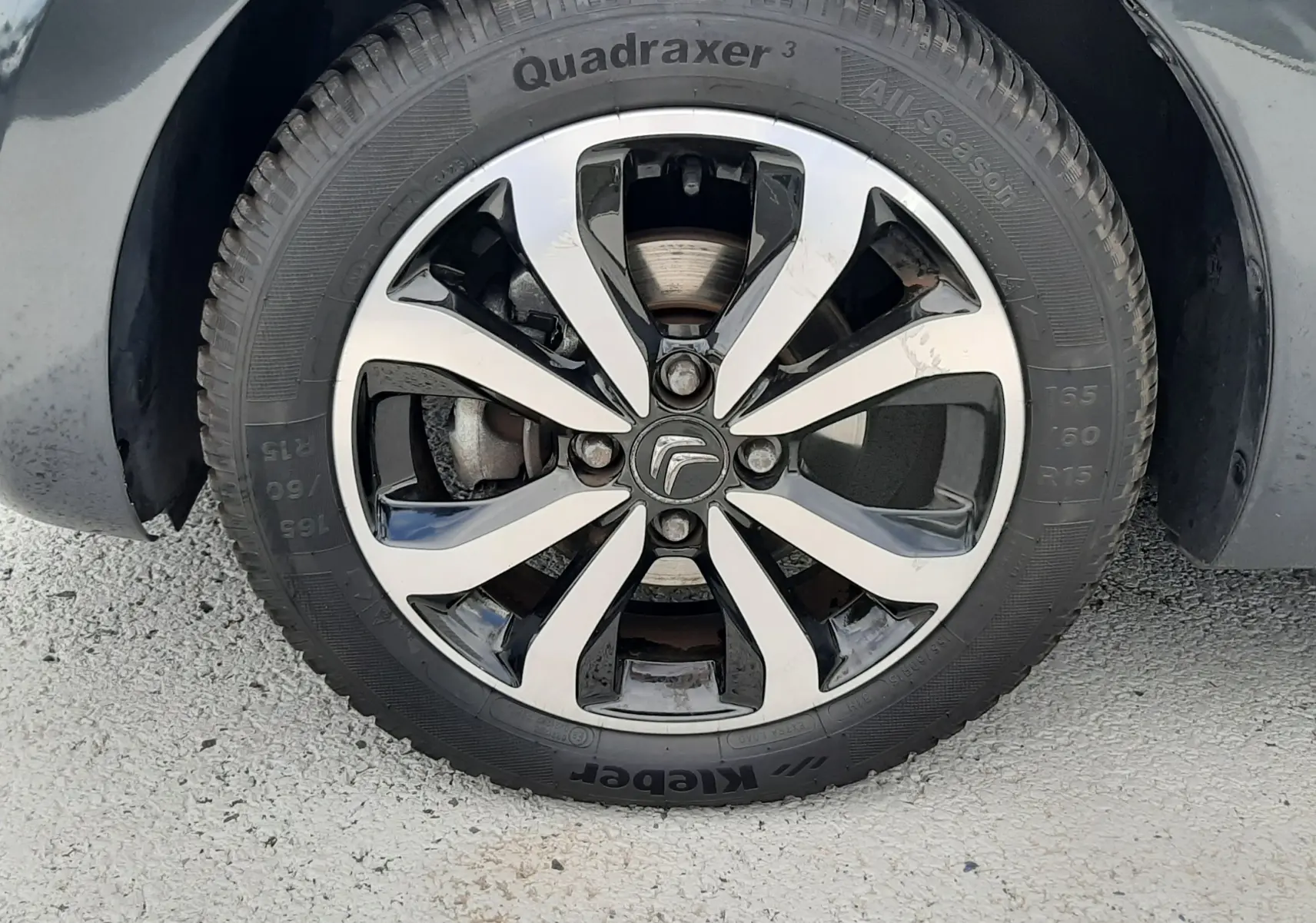 Gros plan sur la jante bicolore noire et argentée d'une Citroën C1 gris foncé, roue avant droite visible.