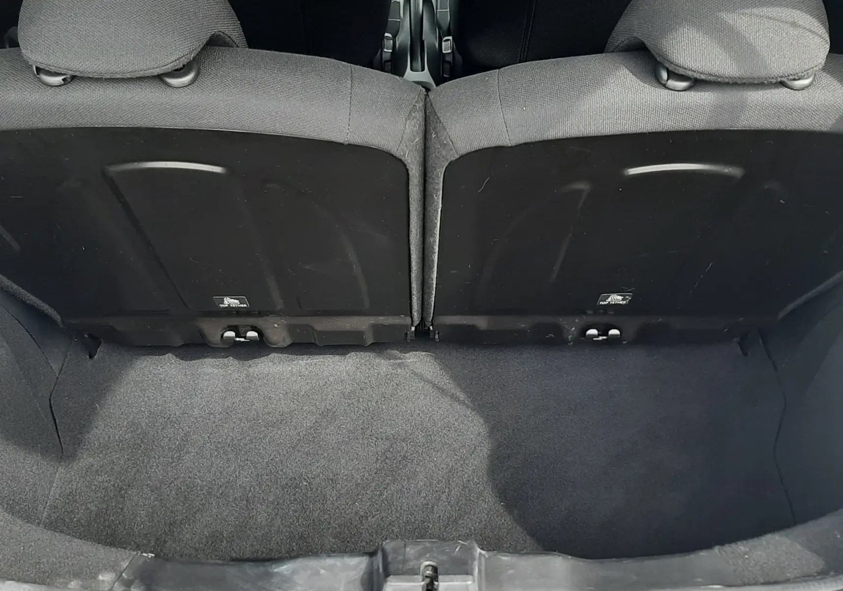 Vue depuis le coffre ouvert d'une Citroën C1 gris foncé 2019, montrant l'intérieur noir et les dossiers arrière des sièges.