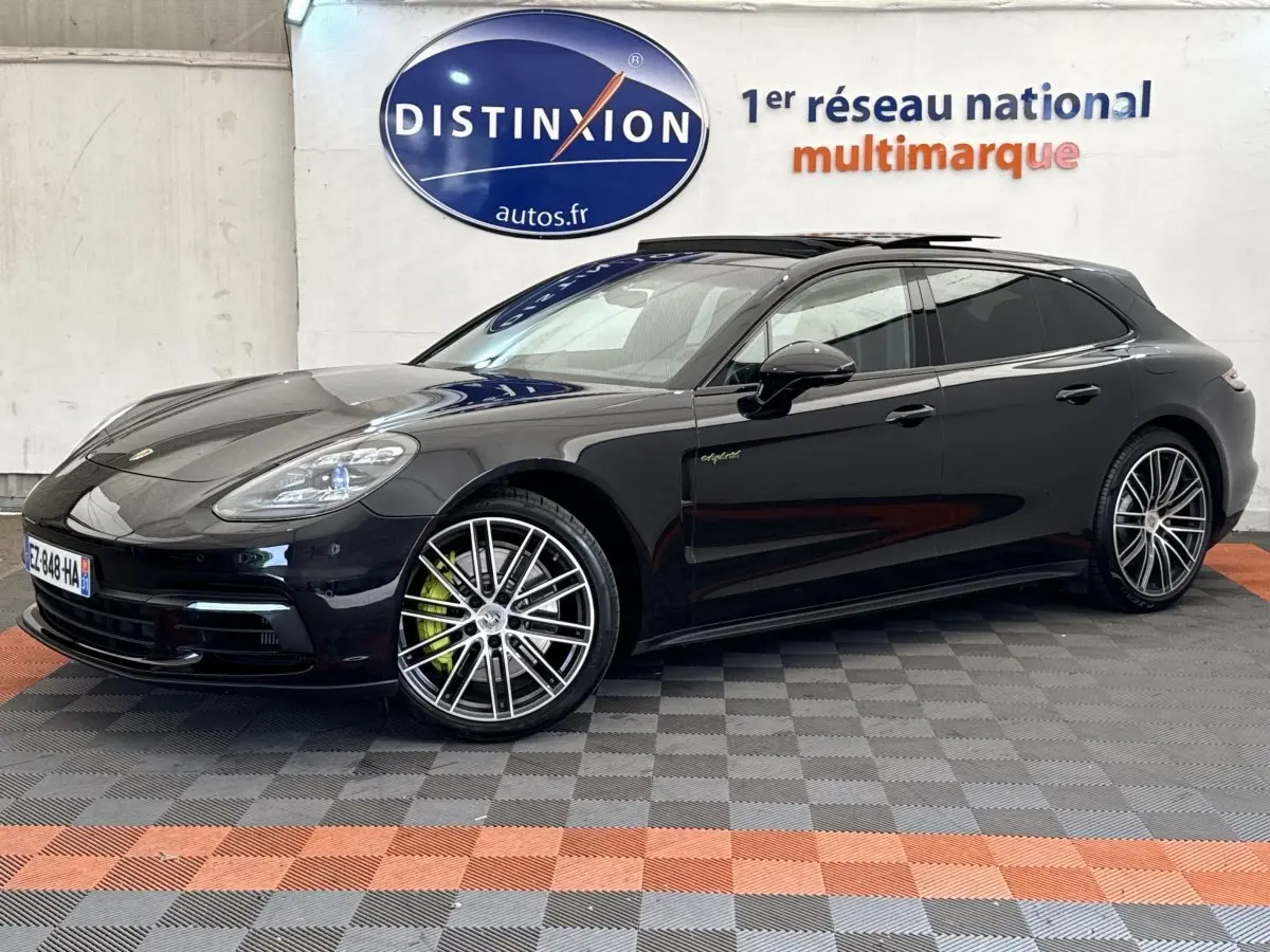 Vue 3/4 avant droite d'une Porsche Panamera 4 E-Hybrid Sport Turismo noire avec jantes alliage et logo "e-hybrid" sur la porte.