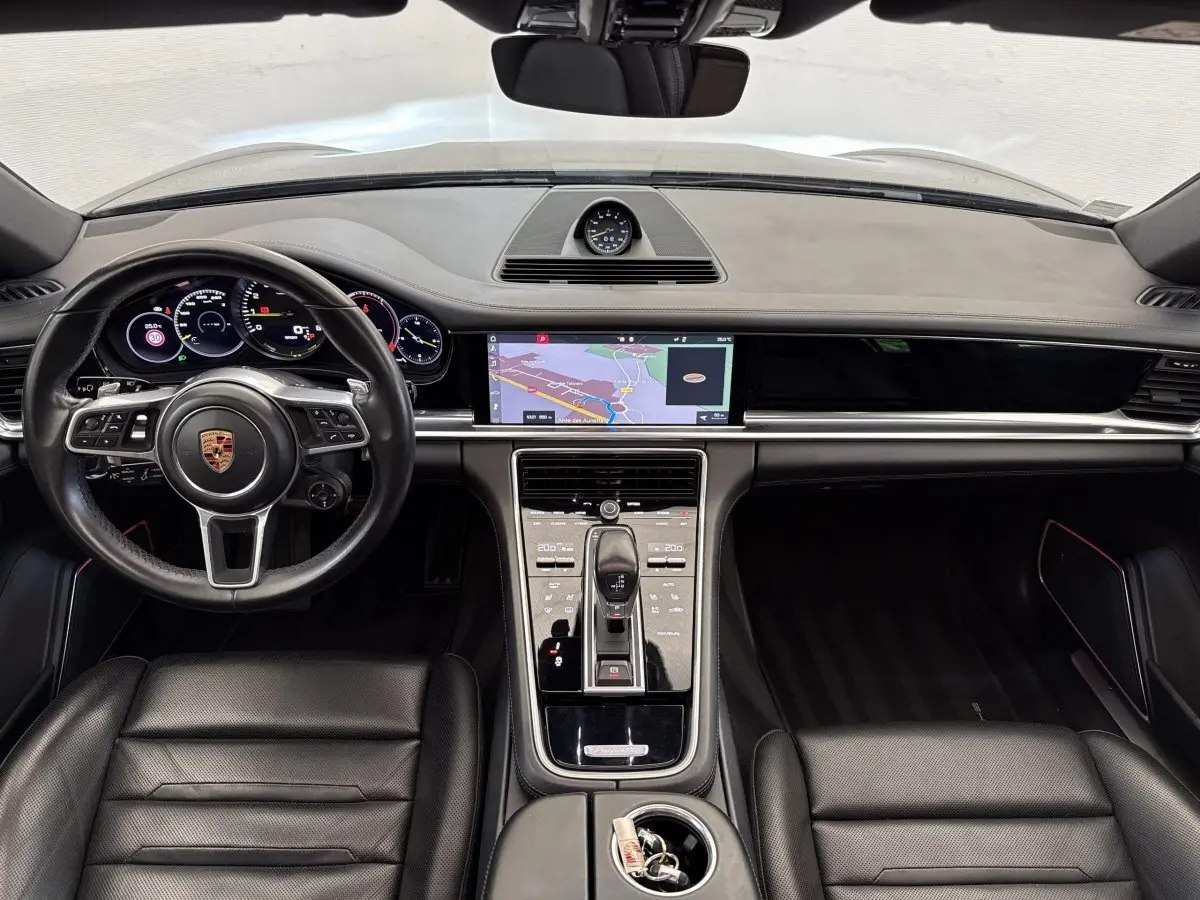 Vue intérieure avant de la Porsche Panamera 4 E-Hybrid Sport Turismo 2018, tableau de bord noir avec écran tactile navigation.