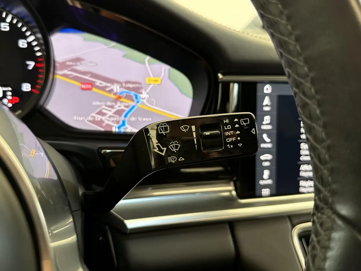 Gros plan sur la commande d’essuie-glace à gauche du volant cuir dans l’habitacle d’une Porsche Panamera 4 E-Hybrid noire.