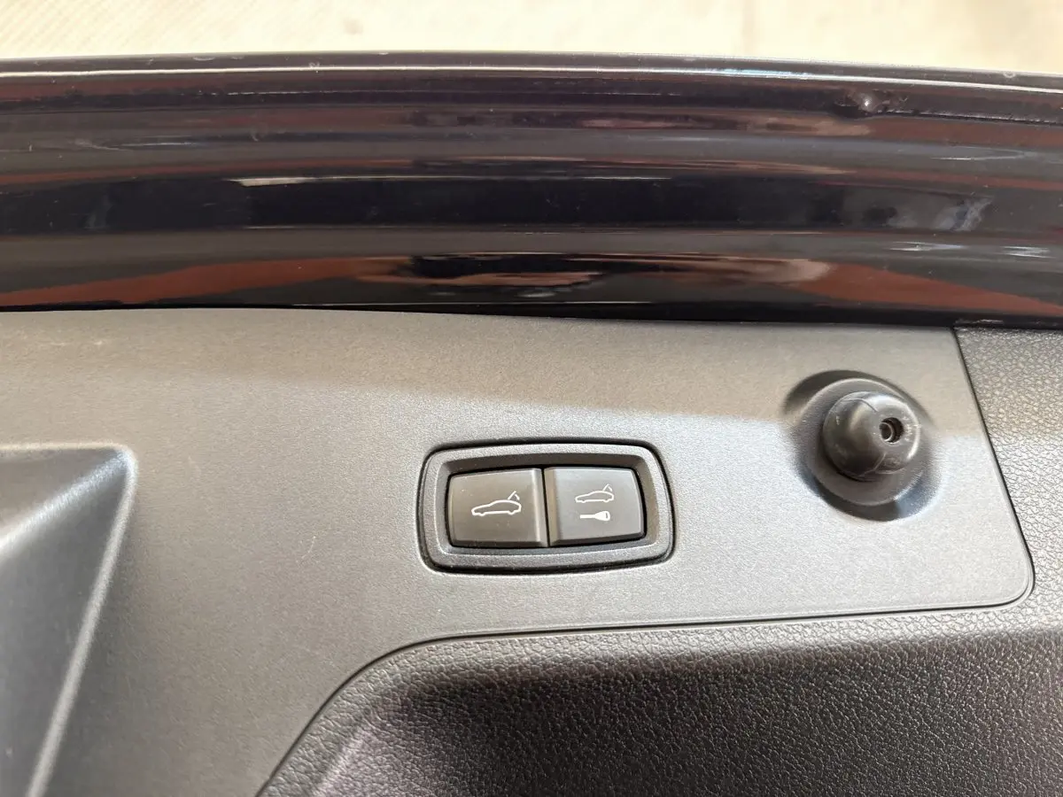 Gros plan sur les boutons d'ouverture électrique du coffre et du hayon sur la porte arrière noire d'une Porsche Panamera 4 E-Hybrid Sport Turismo.