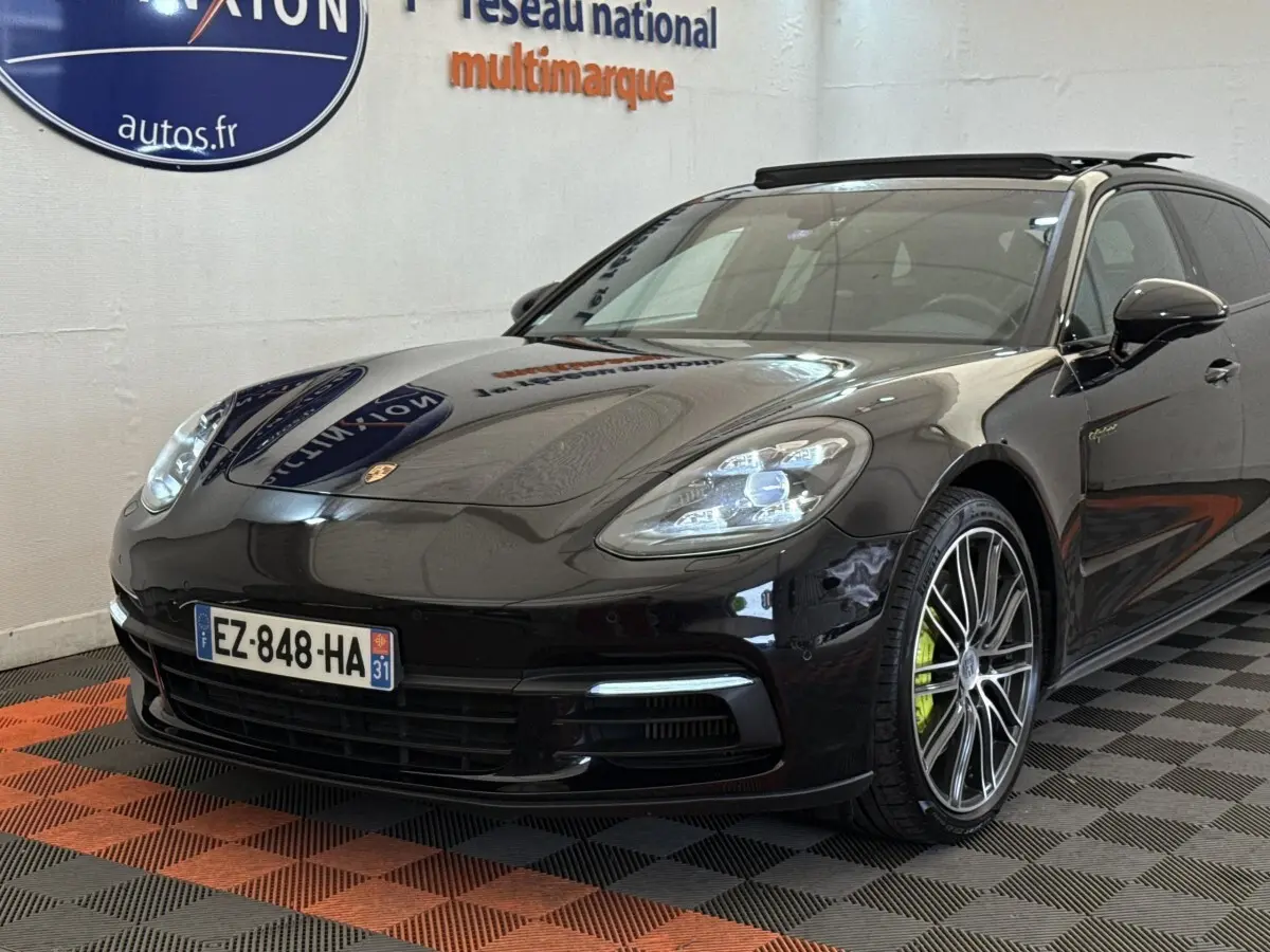 Vue 3/4 avant droite d'une Porsche Panamera 4 E-Hybrid Sport Turismo noire avec jantes alliage et étriers verts.