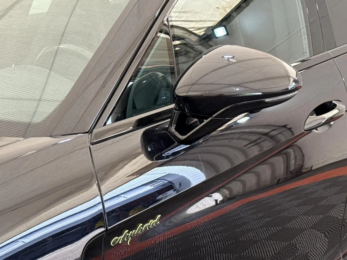 Détail du rétroviseur côté gauche et logo "e-hybrid" sur la porte d'une Porsche Panamera noire.