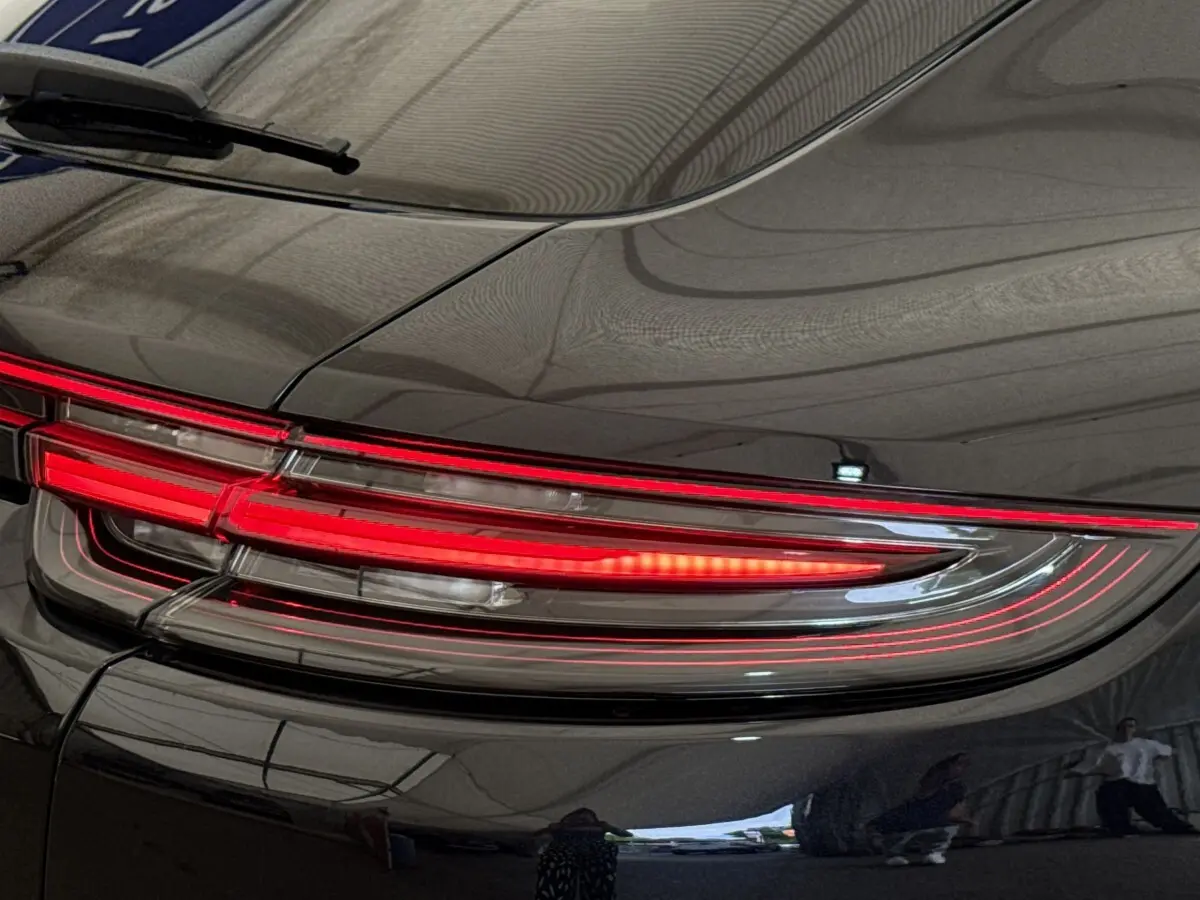 Gros plan sur le feu arrière droit rouge d’une Porsche Panamera 4 E-Hybrid Sport Turismo noire, finition brillante.