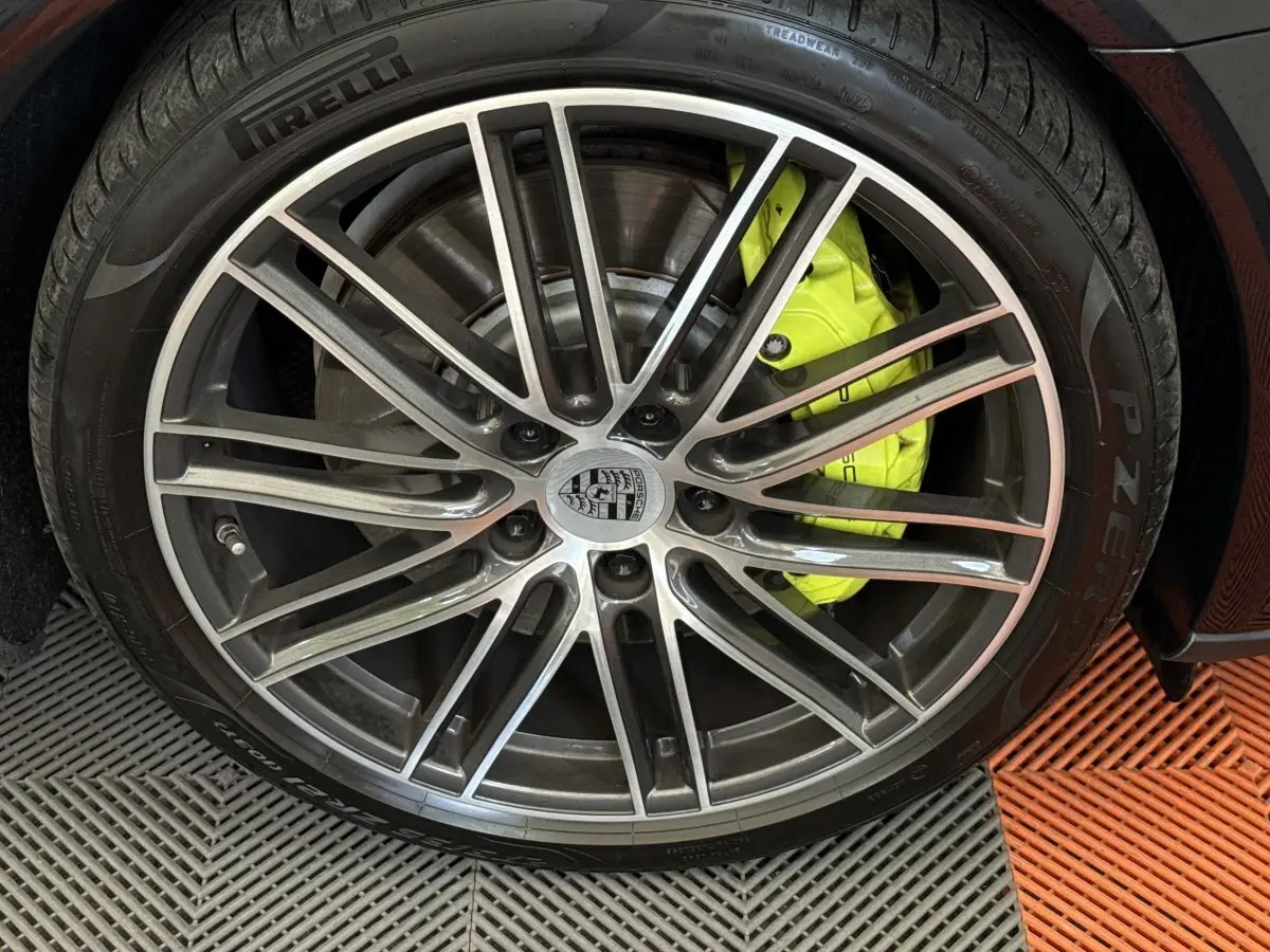 Gros plan sur la jante alliage de la Porsche Panamera 4 E-Hybrid Sport Turismo noire avec étrier de frein jaune vif.
