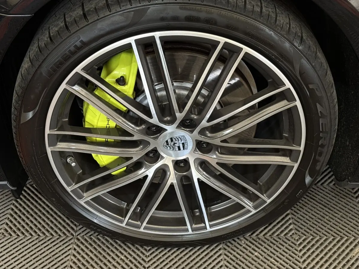 Gros plan sur la jante alliage grise et l’étrier de frein jaune vif d’une Porsche Panamera 4 E-Hybrid Sport Turismo noire.