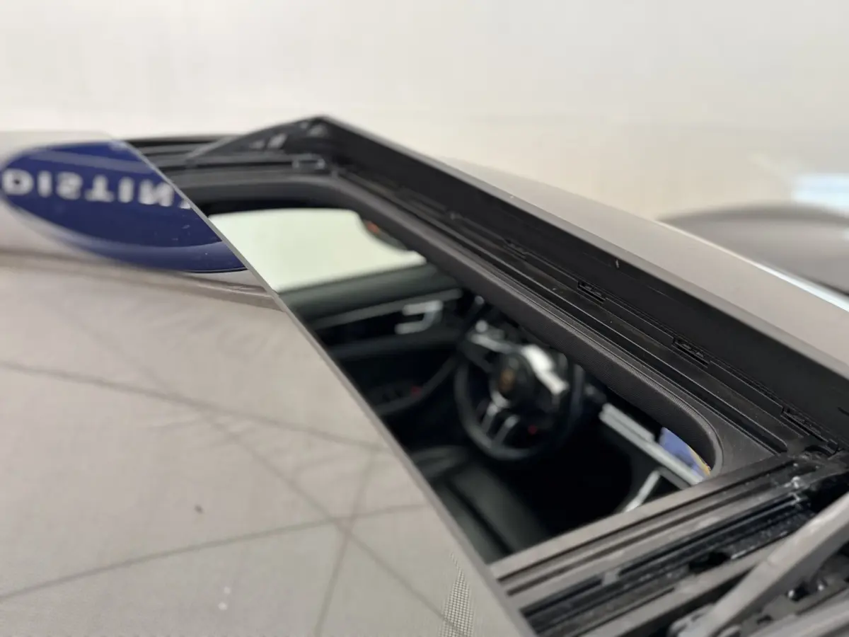 Vue rapprochée du toit ouvrant ouvert d’une Porsche Panamera 4 E-Hybrid Sport Turismo noire, intérieur cuir visible.