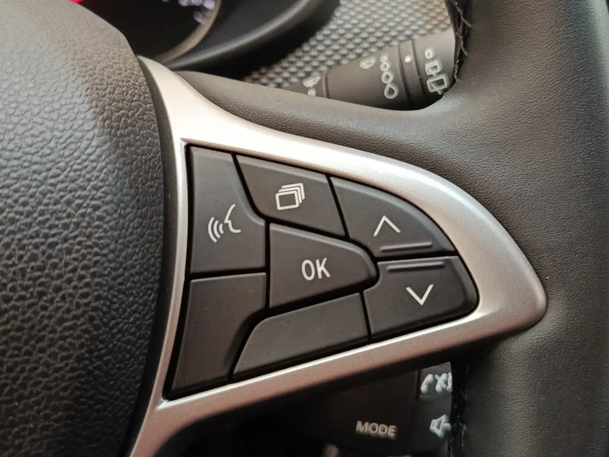 Gros plan sur les commandes multifonctions du volant cuir synthétique de la Dacia Sandero gris clair 2023.