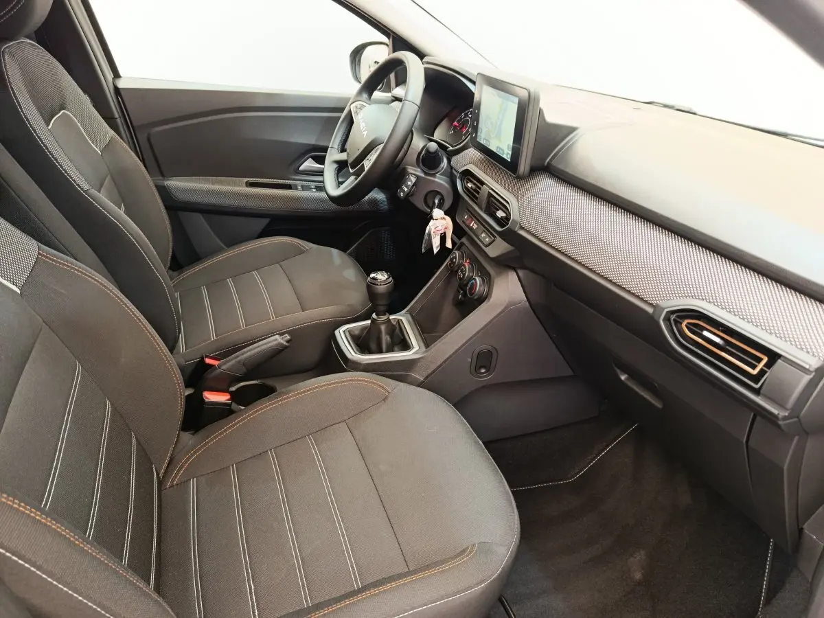 Vue intérieure côté conducteur de la Dacia Sandero Expression EGO-G 100 2023, sièges noirs et tableau de bord avec écran tactile.