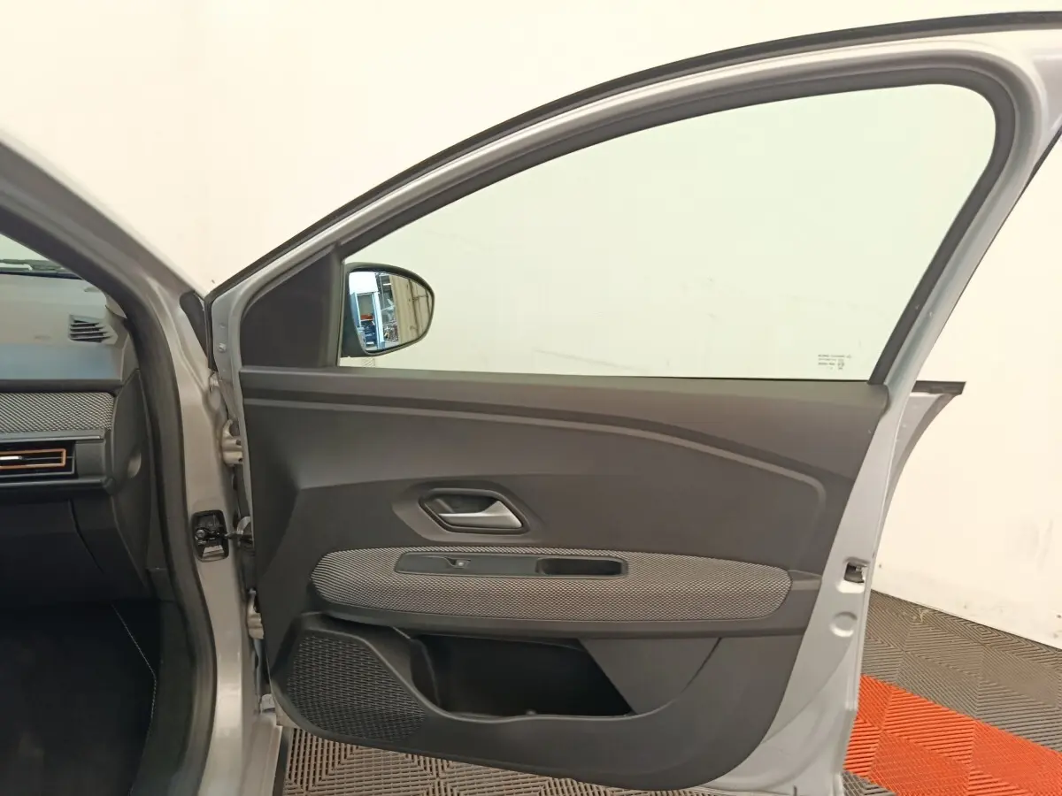 Vue intérieure de la porte avant gauche gris clair d'une Dacia Sandero Expression EGO-G 100 2023, avec garniture noire et tissu gris.