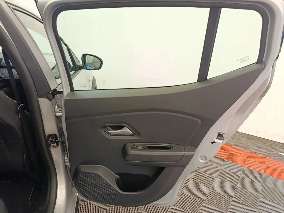 Vue intérieure de la porte arrière gauche gris clair d'une Dacia Sandero Expression EGO-G 2023, avec poignée et commande de vitre.