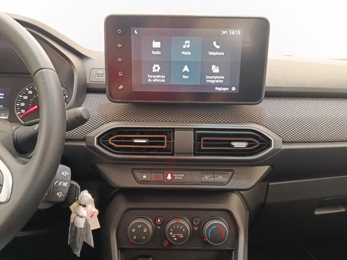 Vue intérieure frontale du tableau de bord de la Dacia Sandero gris clair, avec écran tactile multifonctions et aérateurs hexagonaux.