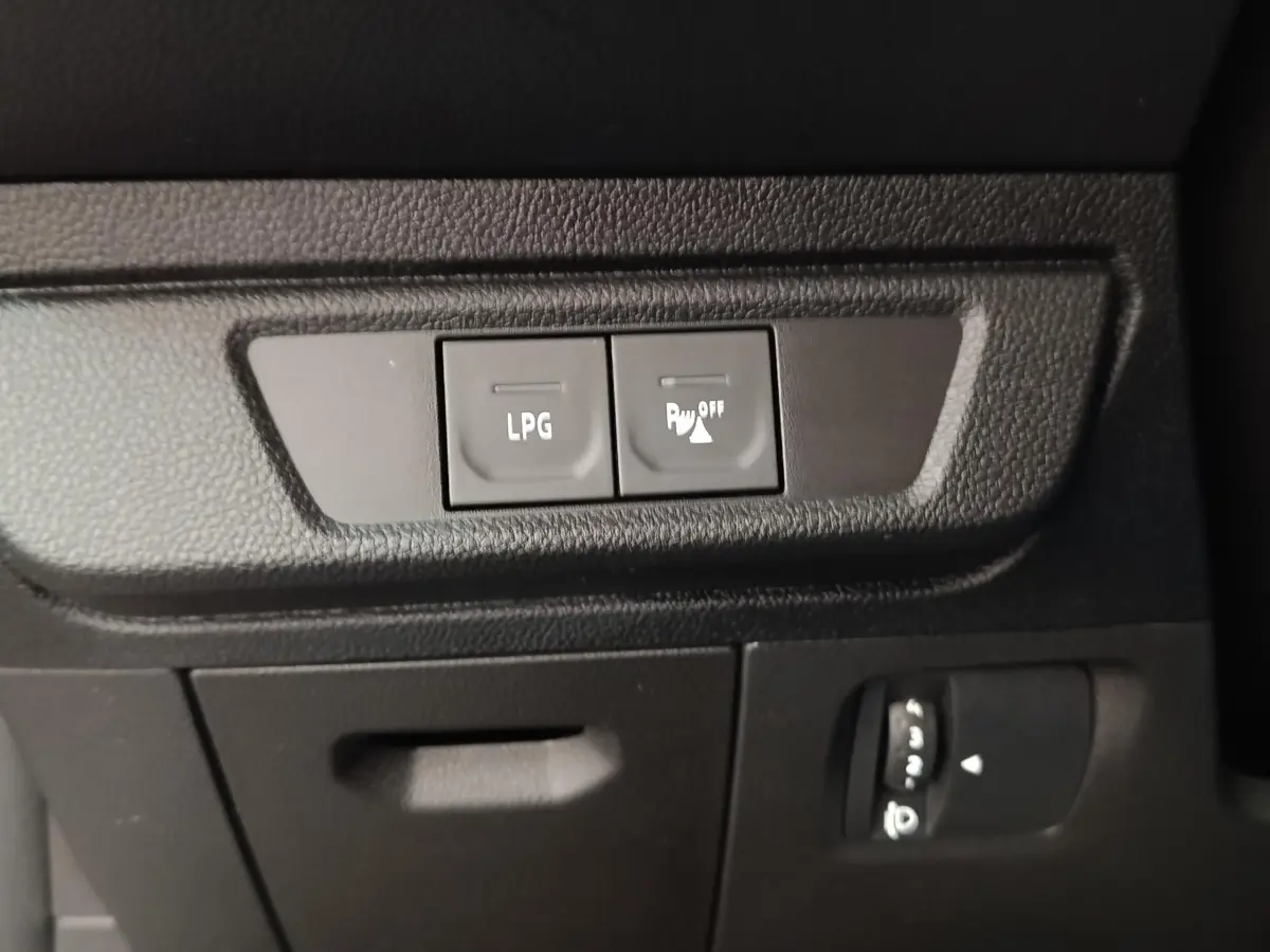 Gros plan sur les boutons LPG et désactivation capteurs de stationnement dans l'habitacle noir du Dacia Sandero gris clair.