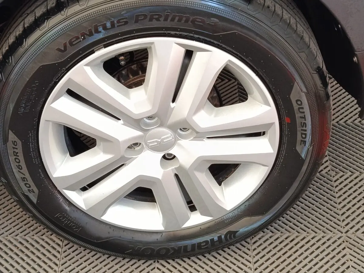 Gros plan sur la roue avant droite d'une Dacia Sandero gris clair avec jante en alliage au design moderne.