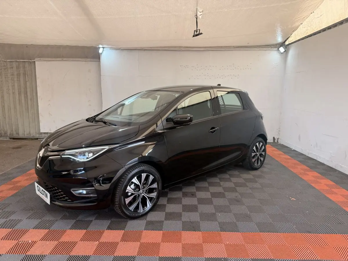 Renault ZOE noire vue 3/4 avant droit, avec jantes alliage et phares LED dans un garage éclairé.