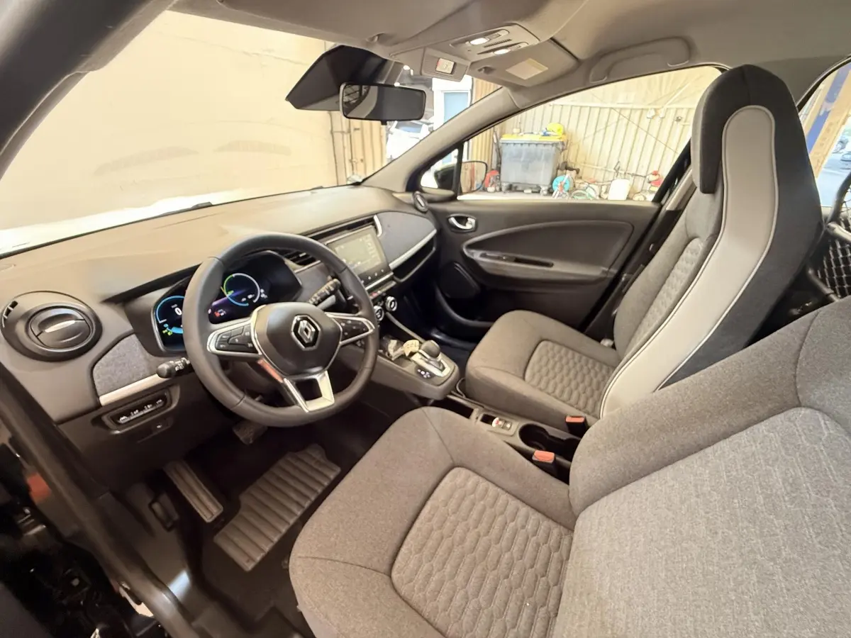 Vue intérieure côté conducteur de la Renault ZOE noire 2024, volant cuir multifonctions et tableau de bord digital.