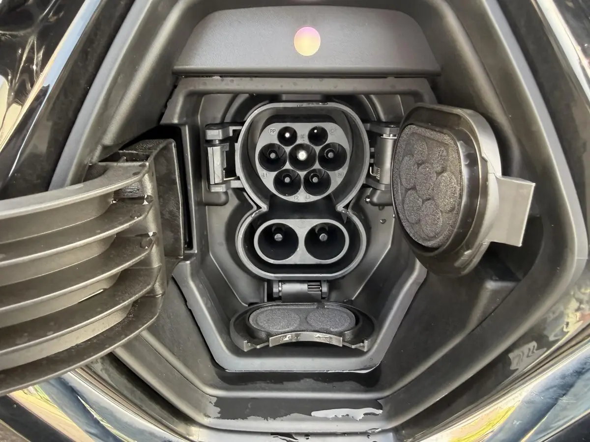 Prise de charge électrique ouverte sur Renault ZOE noire, vue rapprochée du port de recharge côté avant droit.
