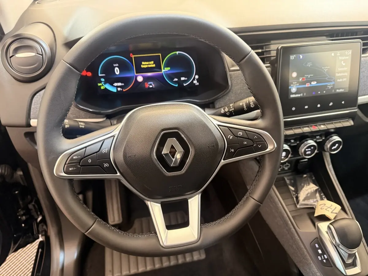 Vue intérieure centrée sur le volant cuir noir et le tableau de bord digital de la Renault ZOE 2024 électrique.