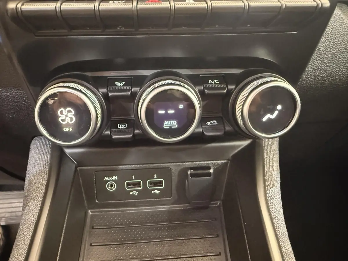 Gros plan sur la console centrale de la Renault ZOE noire, montrant les commandes de climatisation et ports USB.