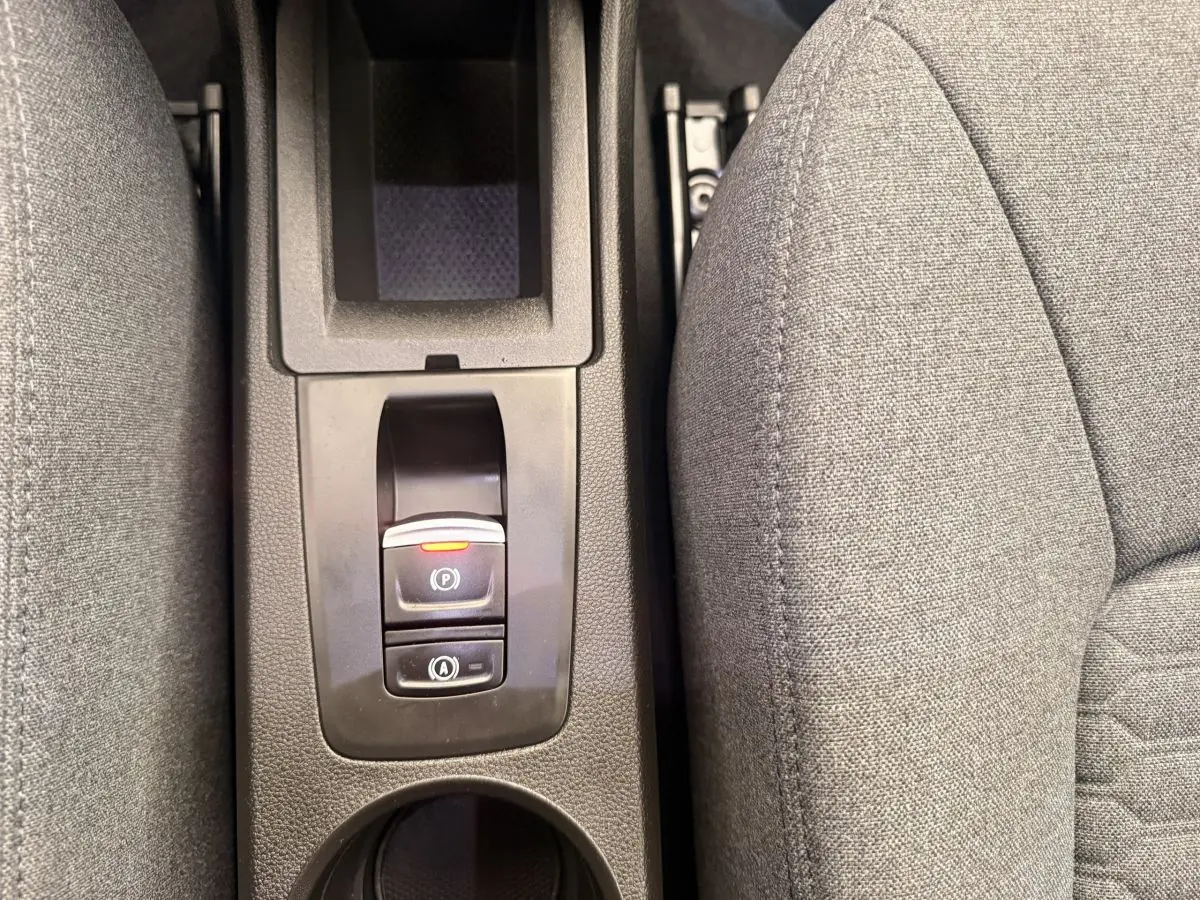 Gros plan sur la console centrale noire avec frein à main électrique et siège tissu gris Renault ZOE 2024.