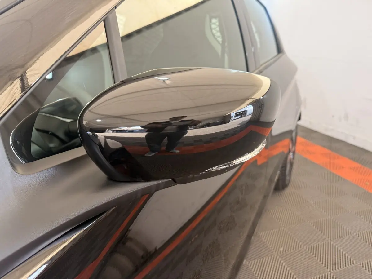 Rétroviseur côté conducteur noir brillant de la Renault ZOE 2024, vue rapprochée sur la portière avant.