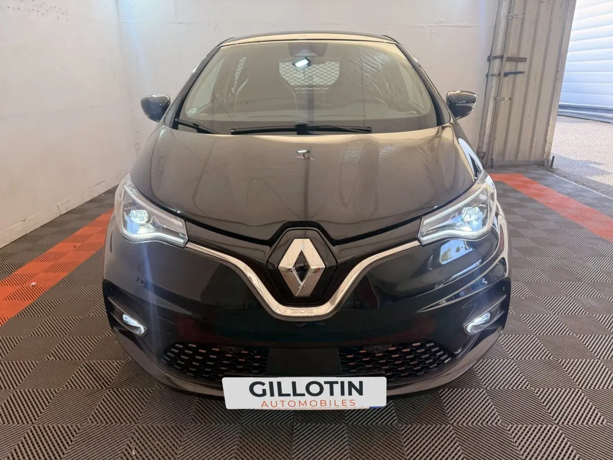 Vue avant d'une Renault ZOE noire électrique 2024 avec phares LED allumés et logo Renault bien visible.