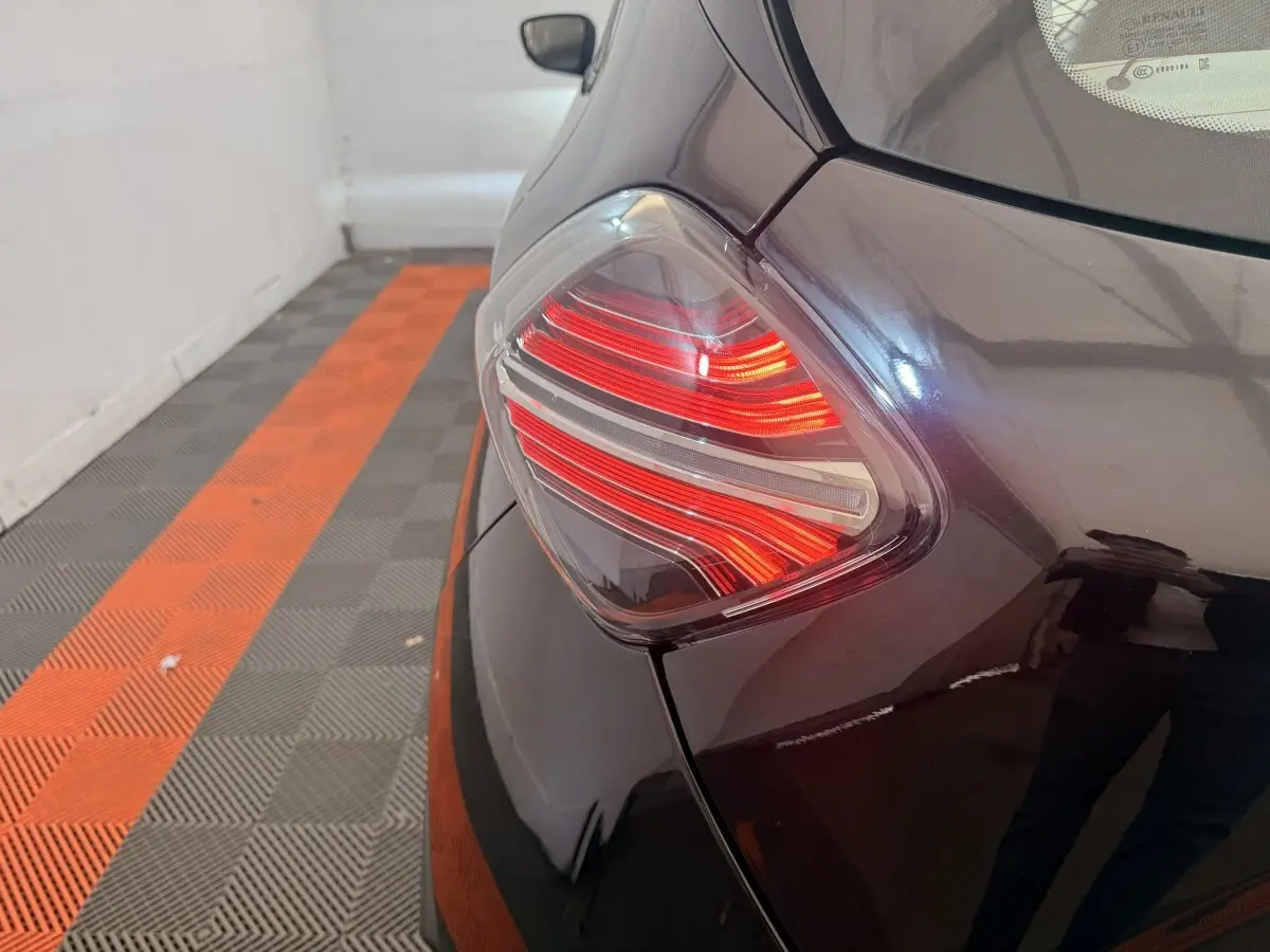 Gros plan sur le feu arrière gauche rouge et blanc d'une Renault ZOE noire, vue depuis l'arrière côté gauche.
