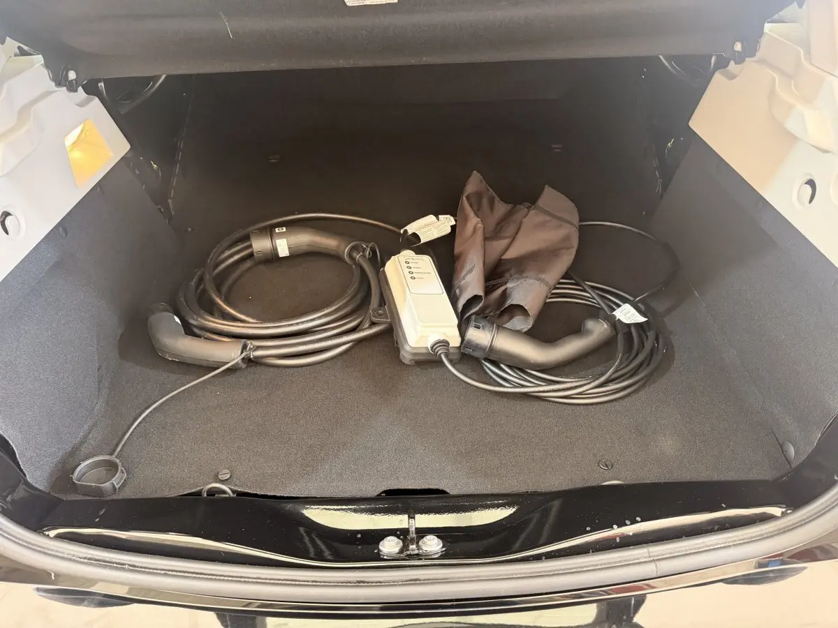 Coffre ouvert d'une Renault ZOE noire 2024 avec câble de charge électrique rangé à l'intérieur.