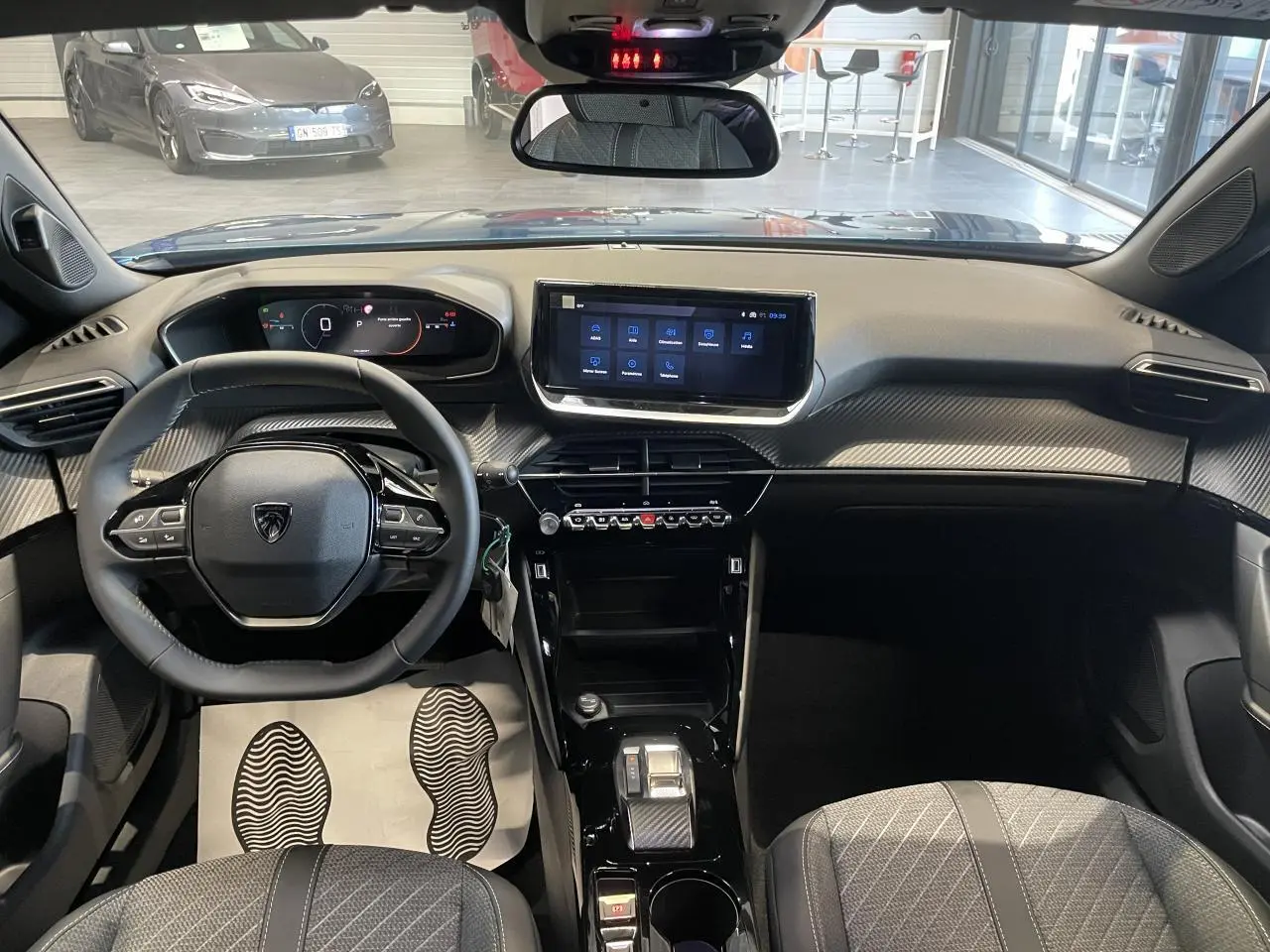 Vue intérieure avant du Peugeot 2008 bleu, tableau de bord avec écran tactile et volant compact cuir noir.