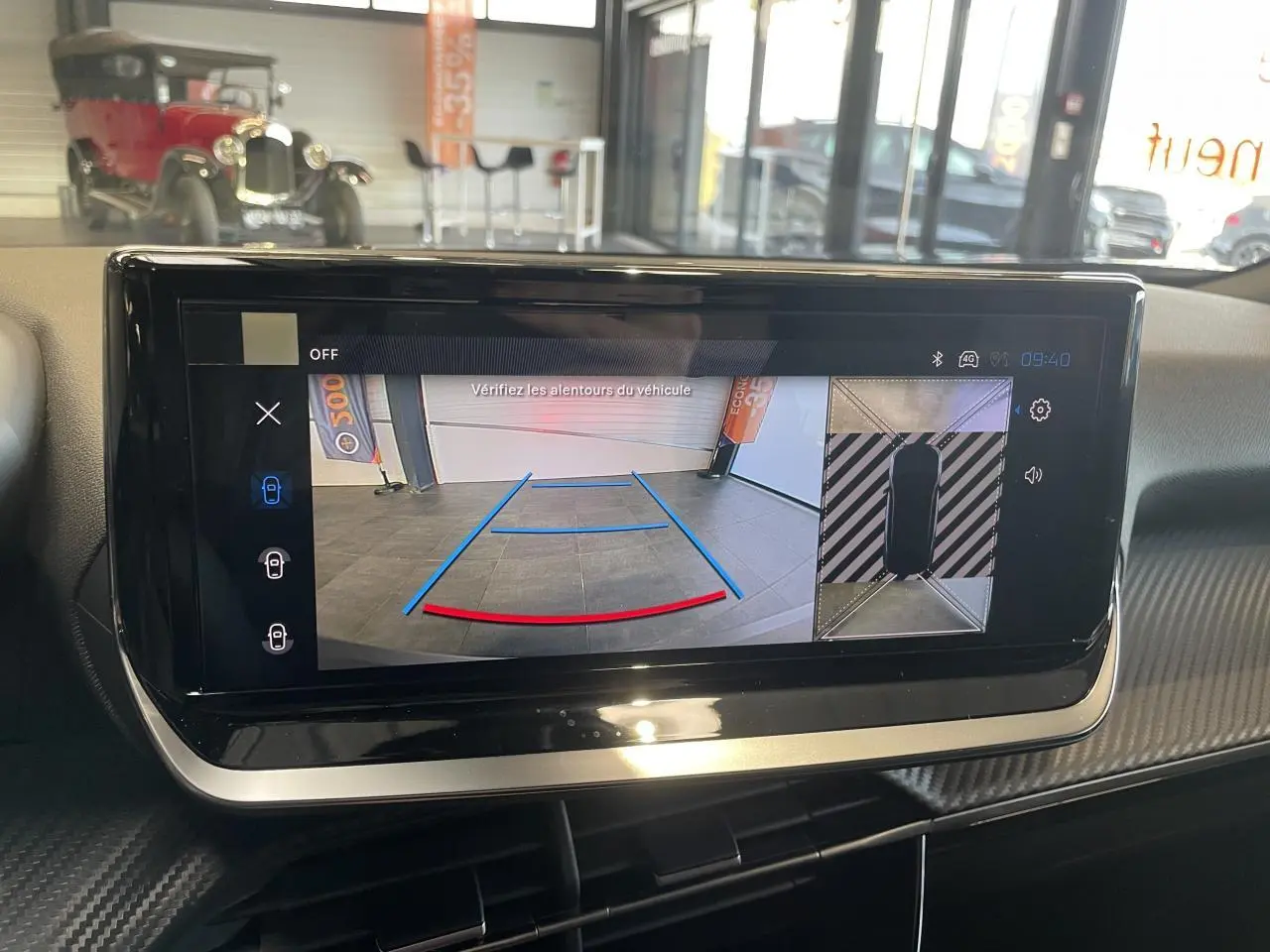 Écran tactile intérieur montrant la caméra de recul et la vue 360° du Peugeot 2008 hybride bleu, planche de bord carbone.
