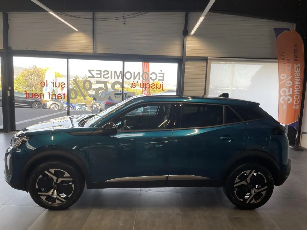 Peugeot 2008 bleu Obsession vue de profil côté gauche en intérieur avec jantes alliage bi-ton et toit noir.