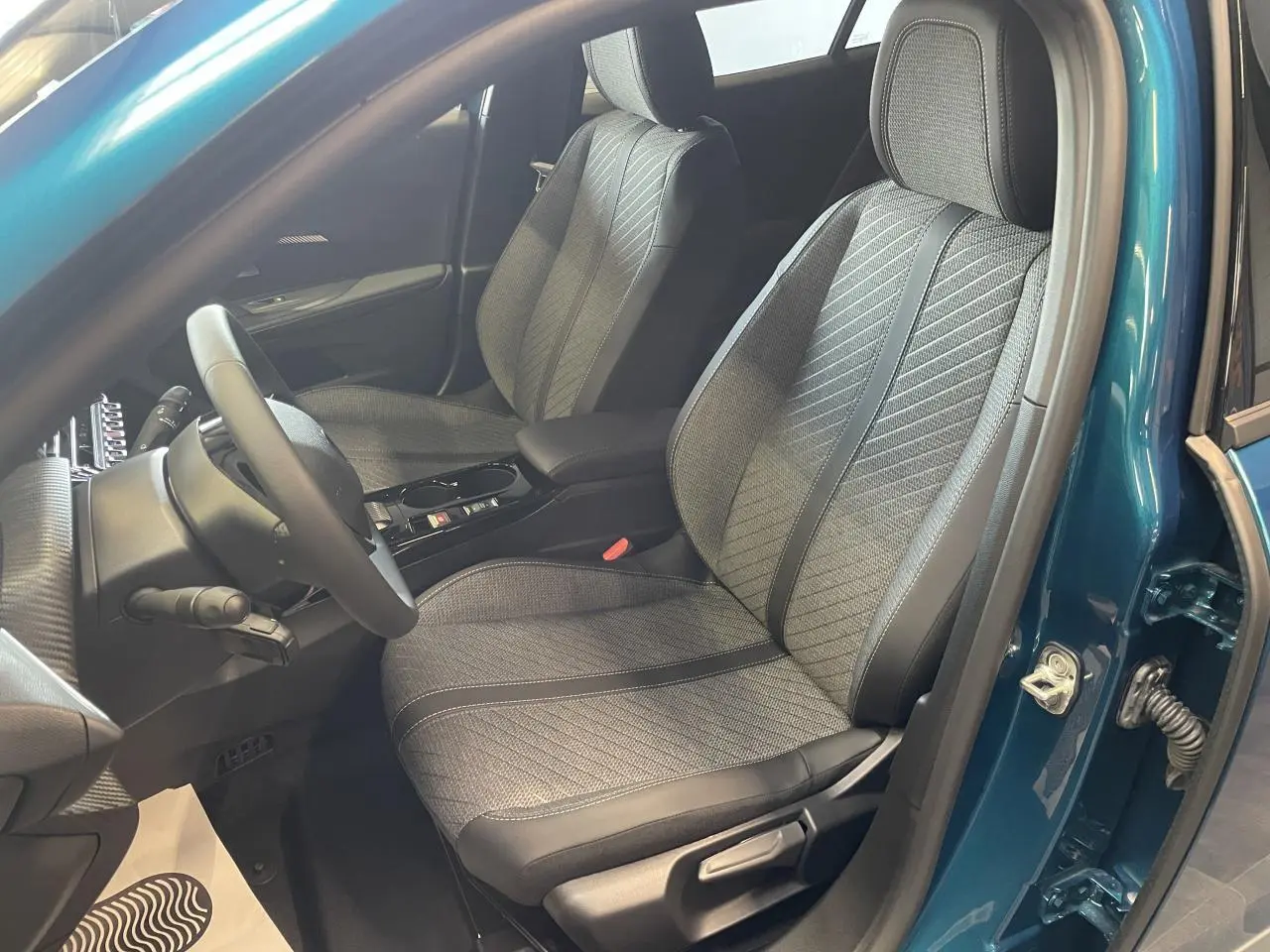 Vue intérieure côté conducteur du Peugeot 2008 bleu, mettant en valeur les sièges tissu et cuir avec surpiqûres Quartz.