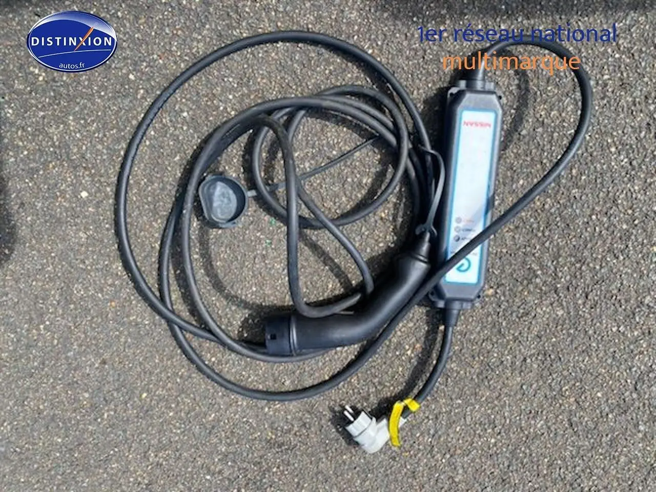 Câble de recharge noir pour Nissan Leaf électrique 40kWh Acenta posé au sol sur un sol goudronné.