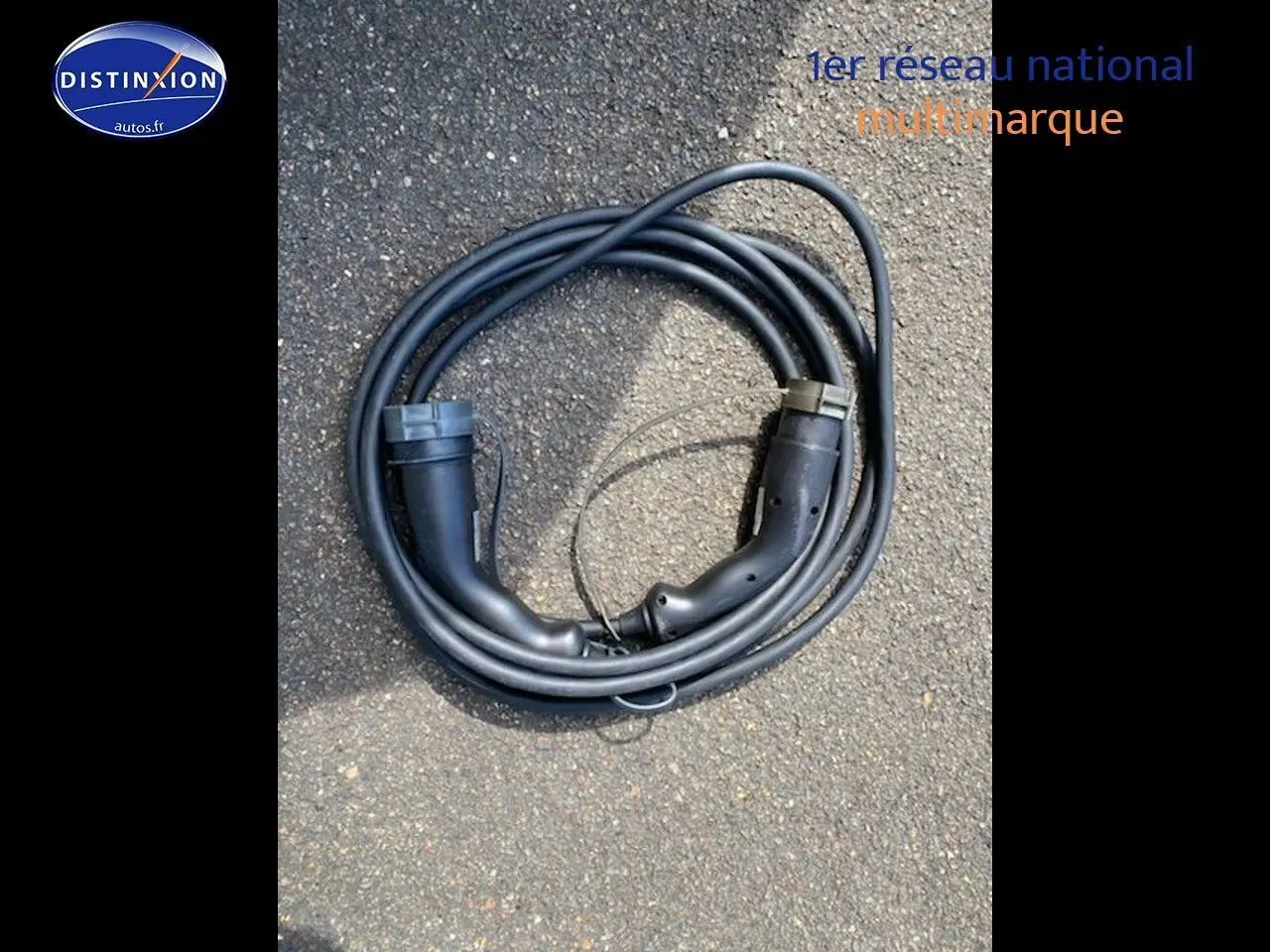 Câble de recharge noir pour Nissan Leaf électrique 40kWh Acenta posé sur sol bitumé, sans véhicule visible.