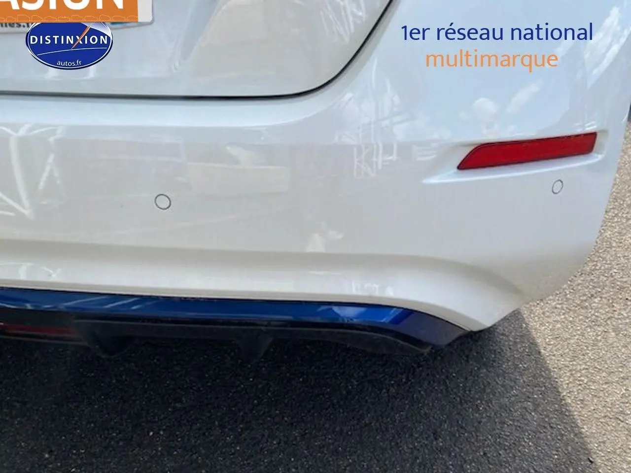 Gros plan sur le pare-chocs arrière blanc nacré d'une Nissan Leaf électrique 40kWh Acenta avec feux rouges et capteurs de recul visibles.