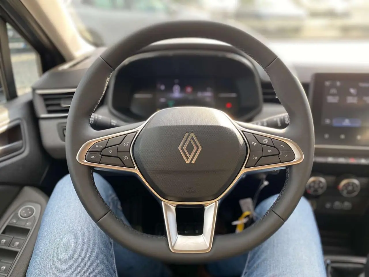 Vue centrée sur le volant noir de la Renault Clio 2025 avec commandes intégrées et tableau de bord numérique flou.