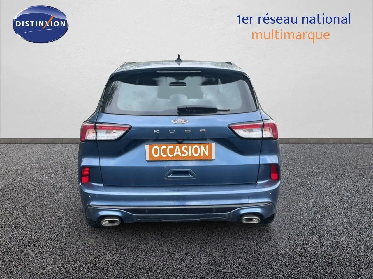 Vue arrière d'un Ford Kuga 2024 bleu chrome métal avec double sortie d'échappement et badge ST-LINE visible.