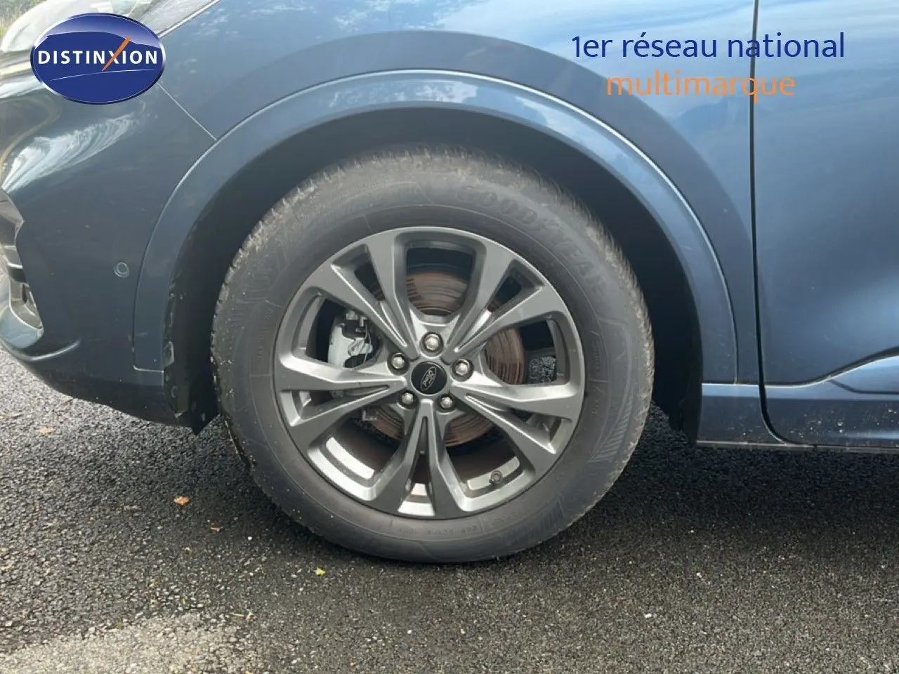 Gros plan sur la roue avant droite d’un Ford Kuga bleu chrome métal, mettant en valeur la jante alliage et le passage de roue.